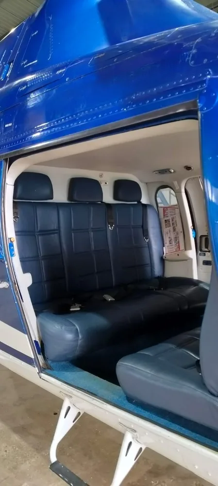 View of the blue leather passenger seats inside the helicopter cabin, looking towards the rear.