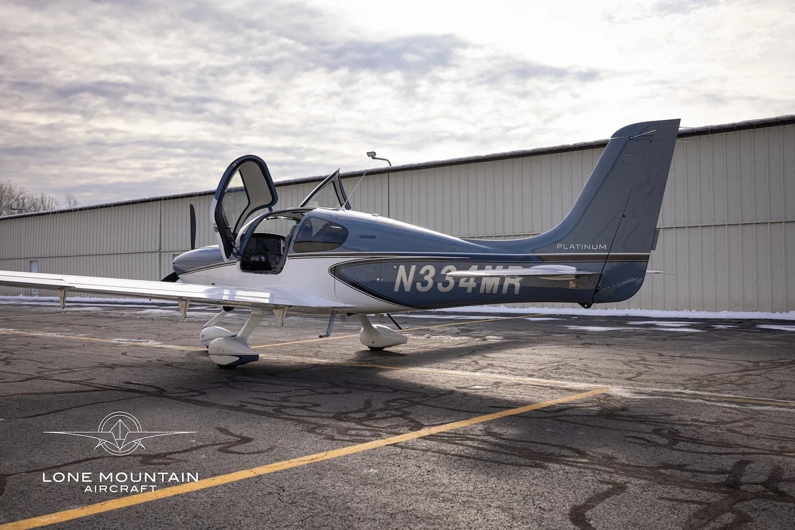 A rear-side view of the Cirrus SR20 aircraft, N334MR, with its gull-wing doors open.