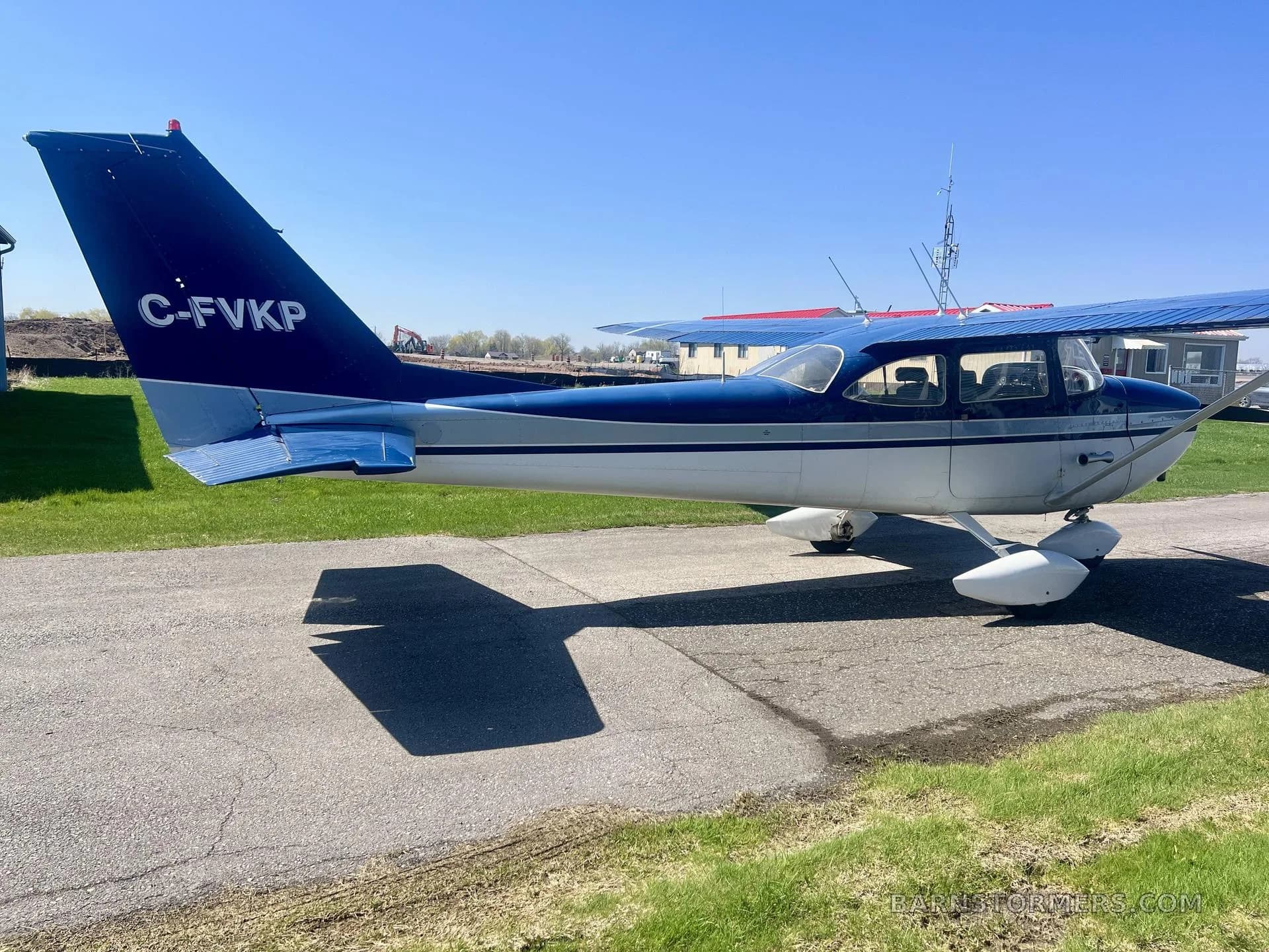 A blue and white 1967 Cessna 172H, registration C-FVKP, parked on an tarmac, viewed from the rear-right, showing the tail number.