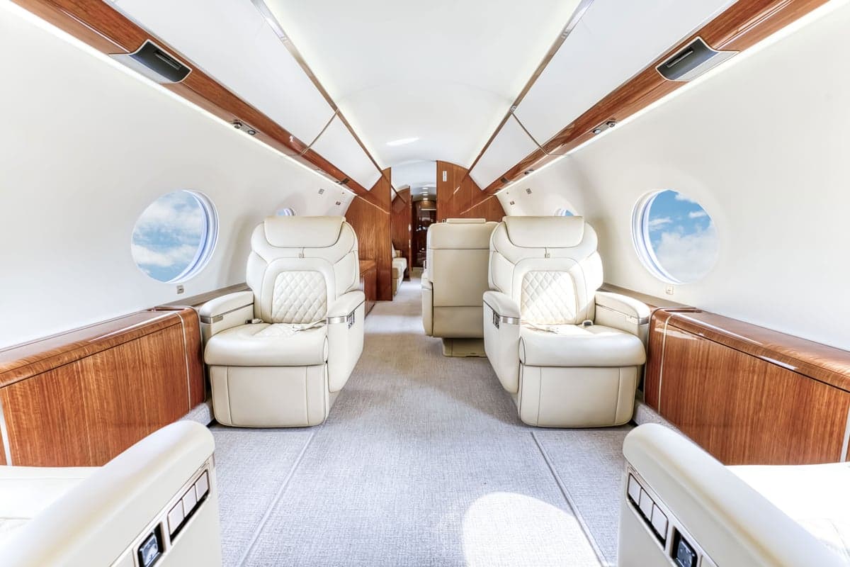 The interior of the aircraft features cream-colored leather seats and wood trim.