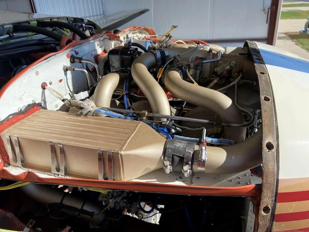 Close-up view of the exposed engine compartment of a Piper Malibu Mirage, showing the engine and associated components.