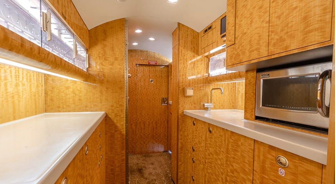 The aircraft's interior features a galley area with wood paneling and a microwave oven.