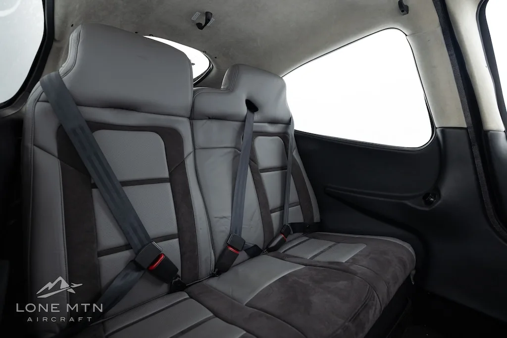 The gray and dark gray rear cabin seats of an aircraft, with seatbelts visible.