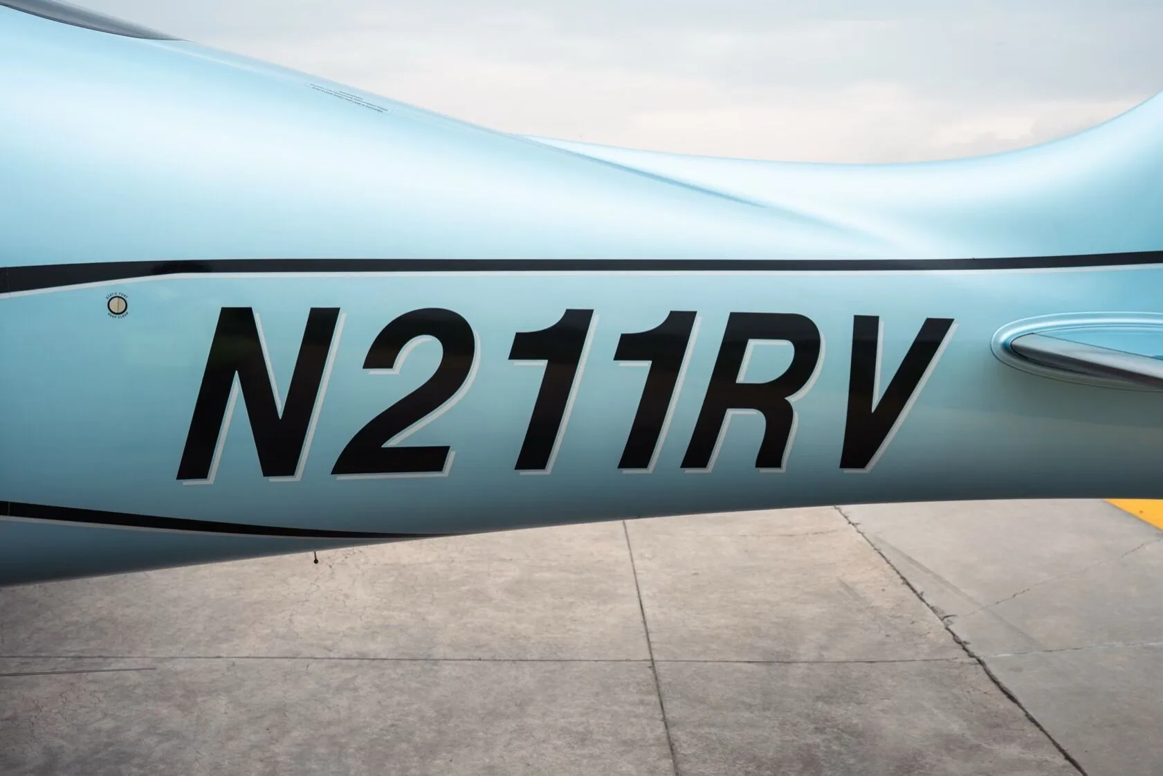 Close-up view of the N211RV registration on the light blue fuselage of the aircraft.