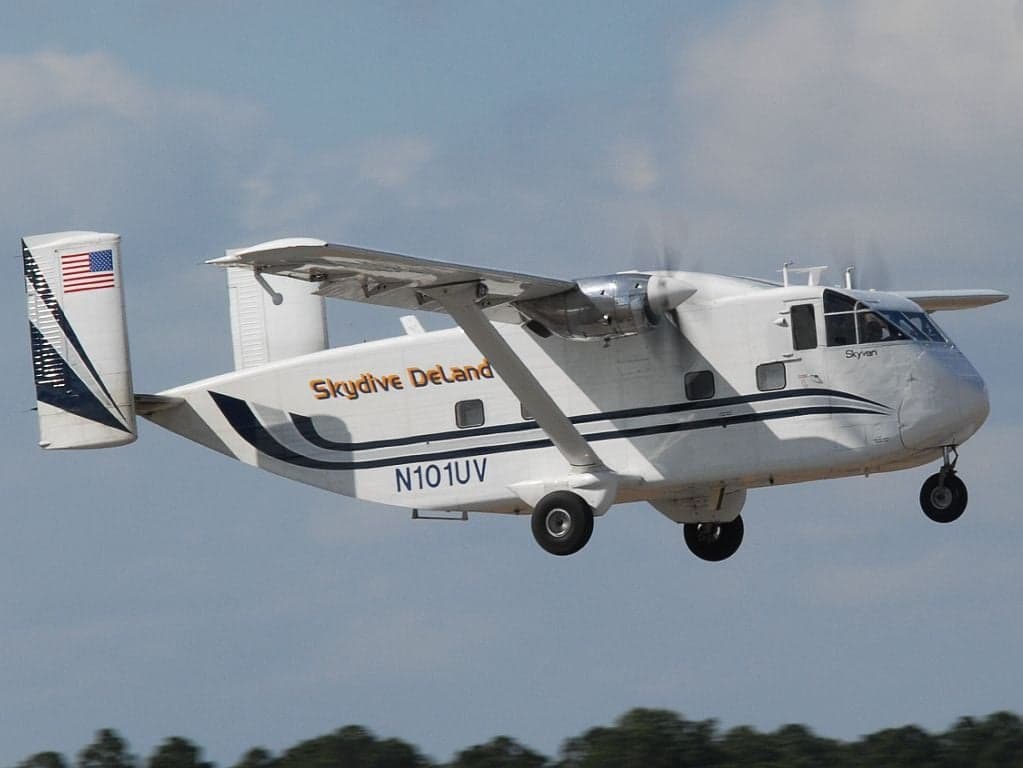 Side view of a white Short Skyvan aircraft with 'Skydive DeLand' livery in flight.