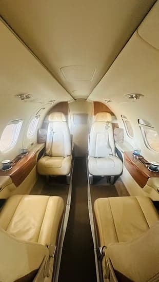 Aisle view of the aircraft's interior with leather seats and wooden accents.