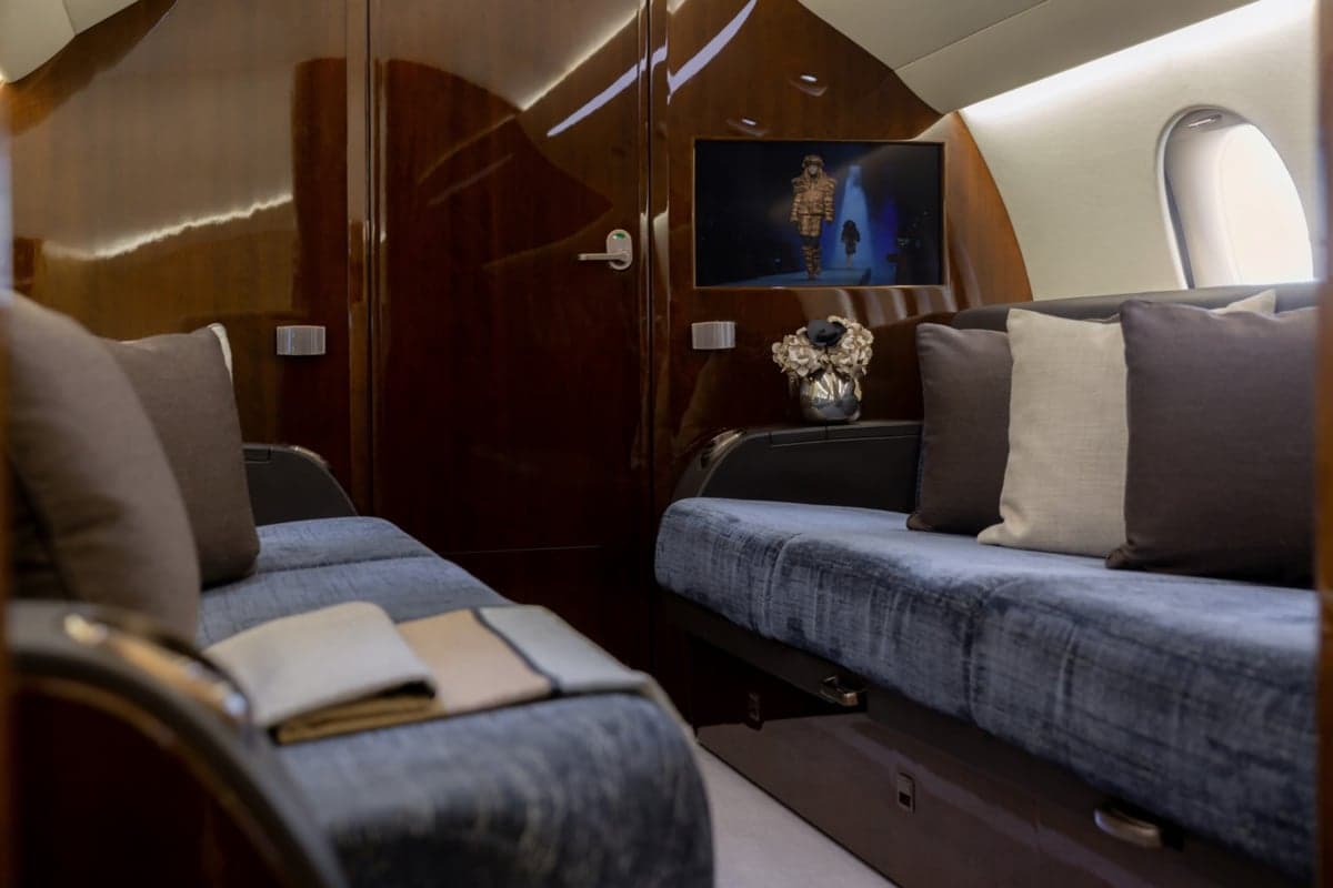 View of the aircraft interior with blue couches and pillows.