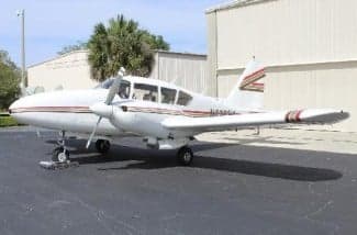 A white and brown striped Piper PA-28-181 Archer II is parked on the tarmac.