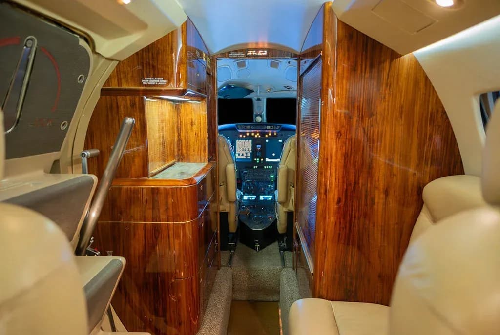 View from the aircraft cabin looking forward into the cockpit, featuring rich wood paneling.