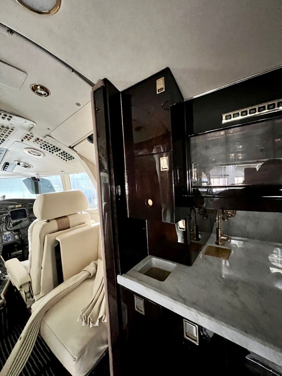 The interior of a Dassault Falcon 900 features white leather seats and dark wood trim.