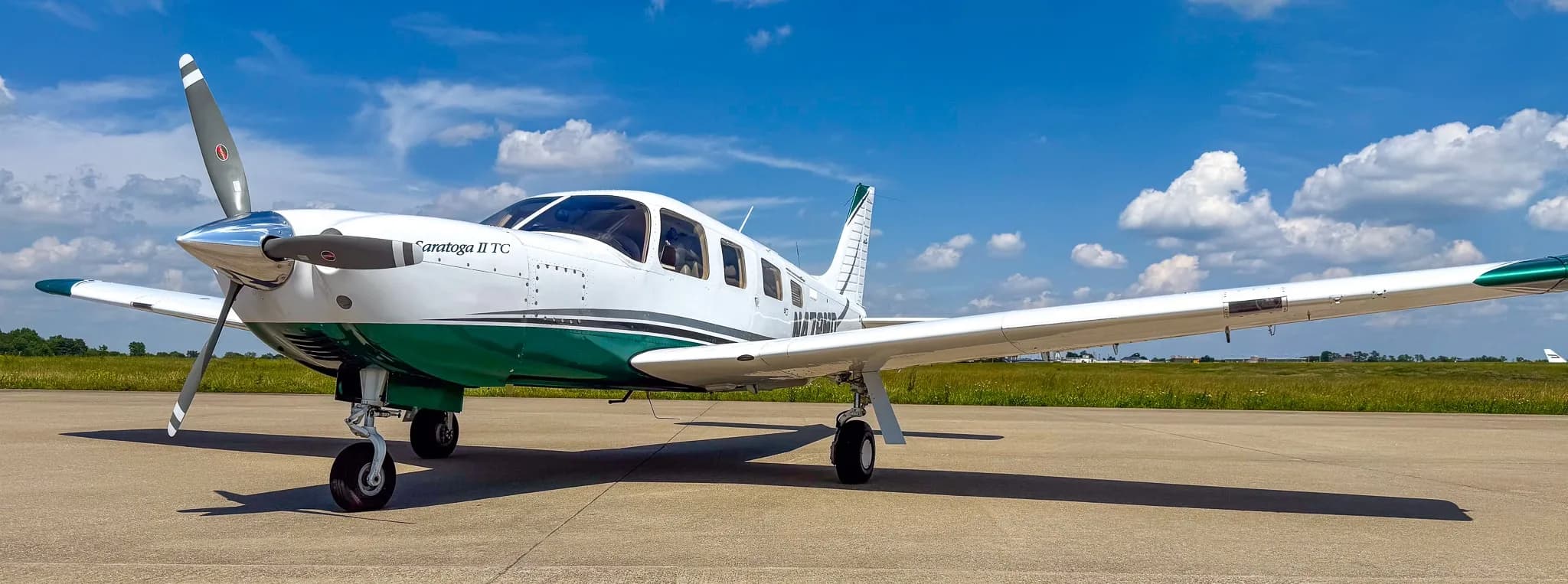 A white and green Piper Saratoga II TC aircraft (N478MD) with its propeller visible, parked on an airfield.