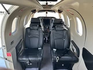 View of the interior of an aircraft cabin with black leather seats facing forward.