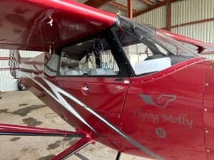 Close up of the cockpit area of a red Cubcrafters aircraft with 'Flying Molly' logo.