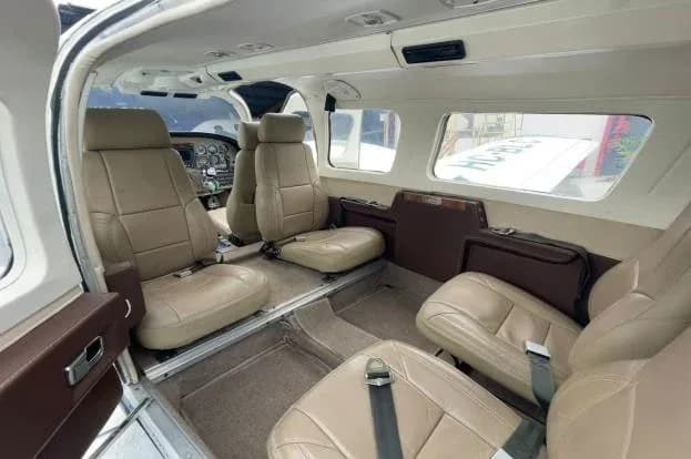 The beige leather interior cabin of a small aircraft with multiple passenger seats.