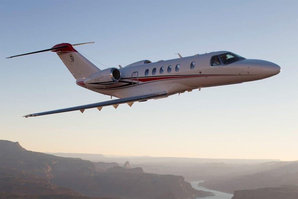 A Citation CJ4 in flight with a red and white paint scheme.