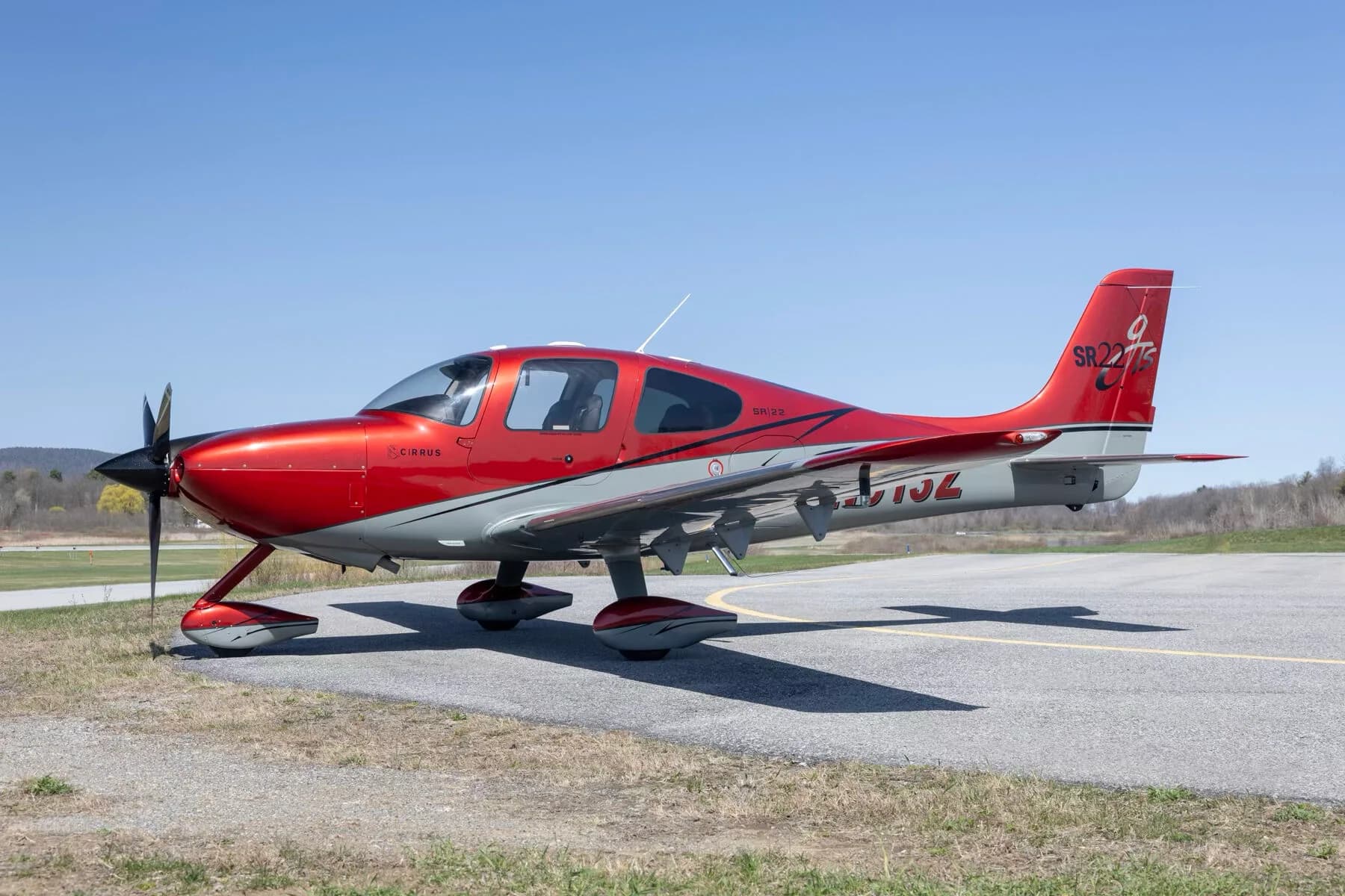 A red and grey Cirrus SR22T aircraft (N513Z) parked on an asphalt runway.
