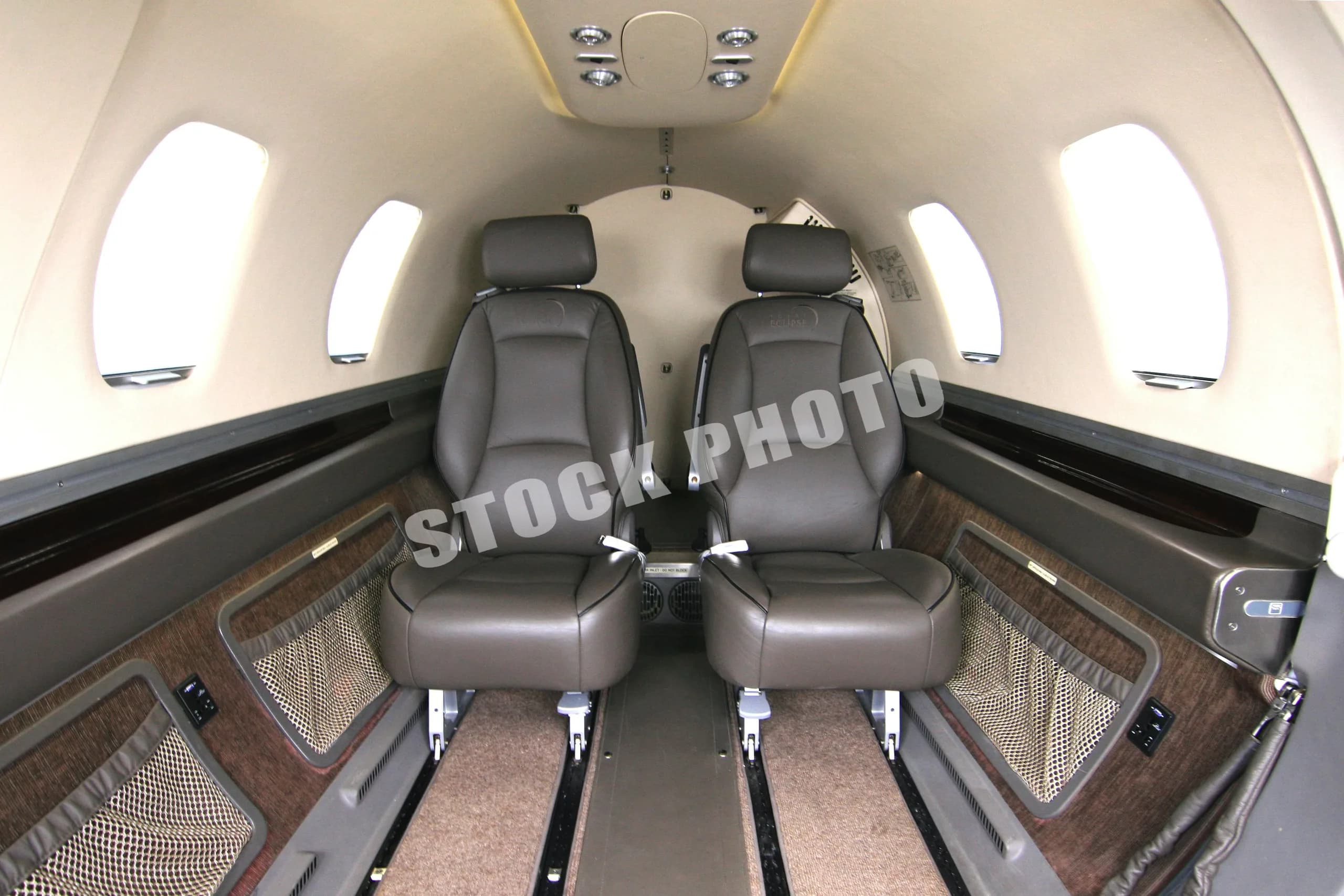 A view of the Eclipse 500 cabin interior, showing two brown leather passenger seats facing forward.