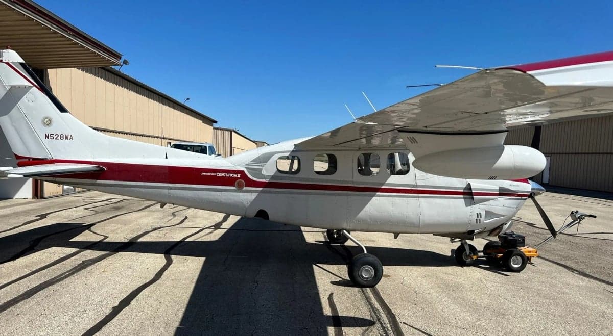 Three-quarter rear view of a red and white Cessna Centurion II aircraft, registration N528WA, parked on an airfield.