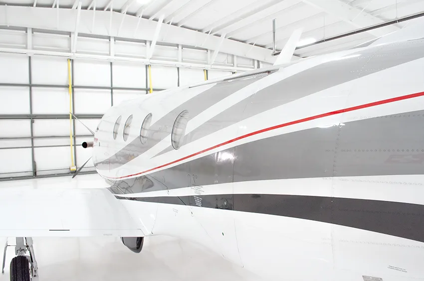 A close-up of the cockpit window and the red "PILATUS" logo on the white fuselage of the aircraft.