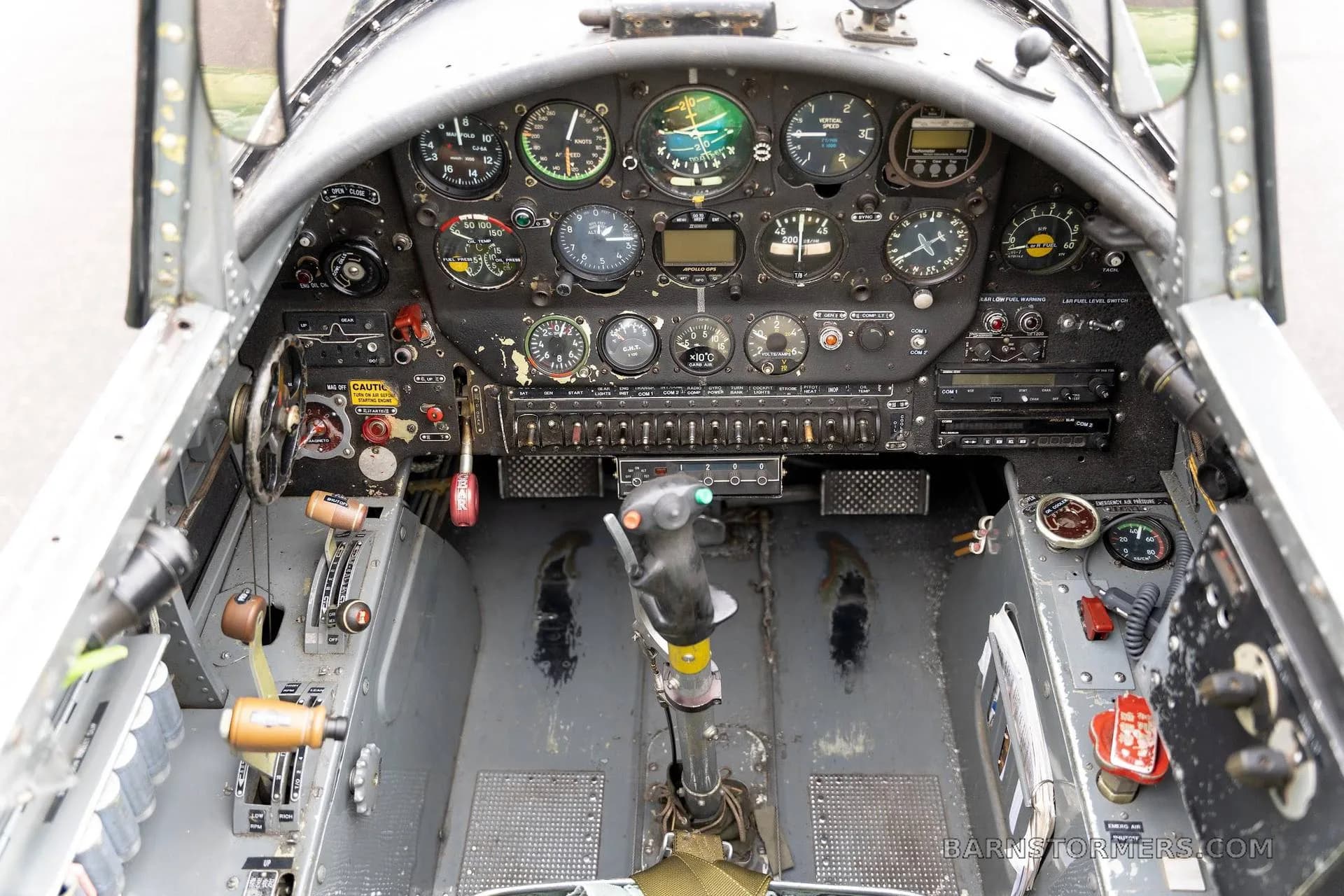 A detailed view of the Nanchang CJ-6 cockpit, showing the instrument panel, control stick, and switches.