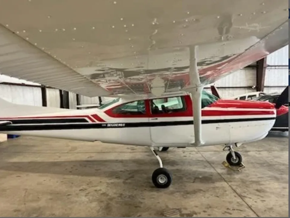 Side view of a red and white Cessna 182 Skylane parked inside a hangar.