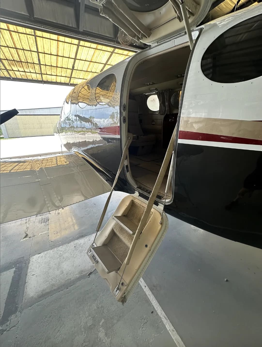 The open cabin door and retractable steps of a twin-engine aircraft, showing a glimpse of the interior.