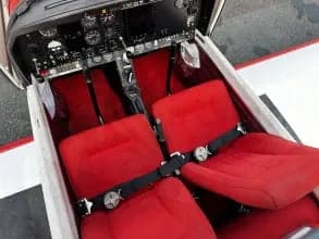 View of the red seats and cockpit inside the aircraft cabin.