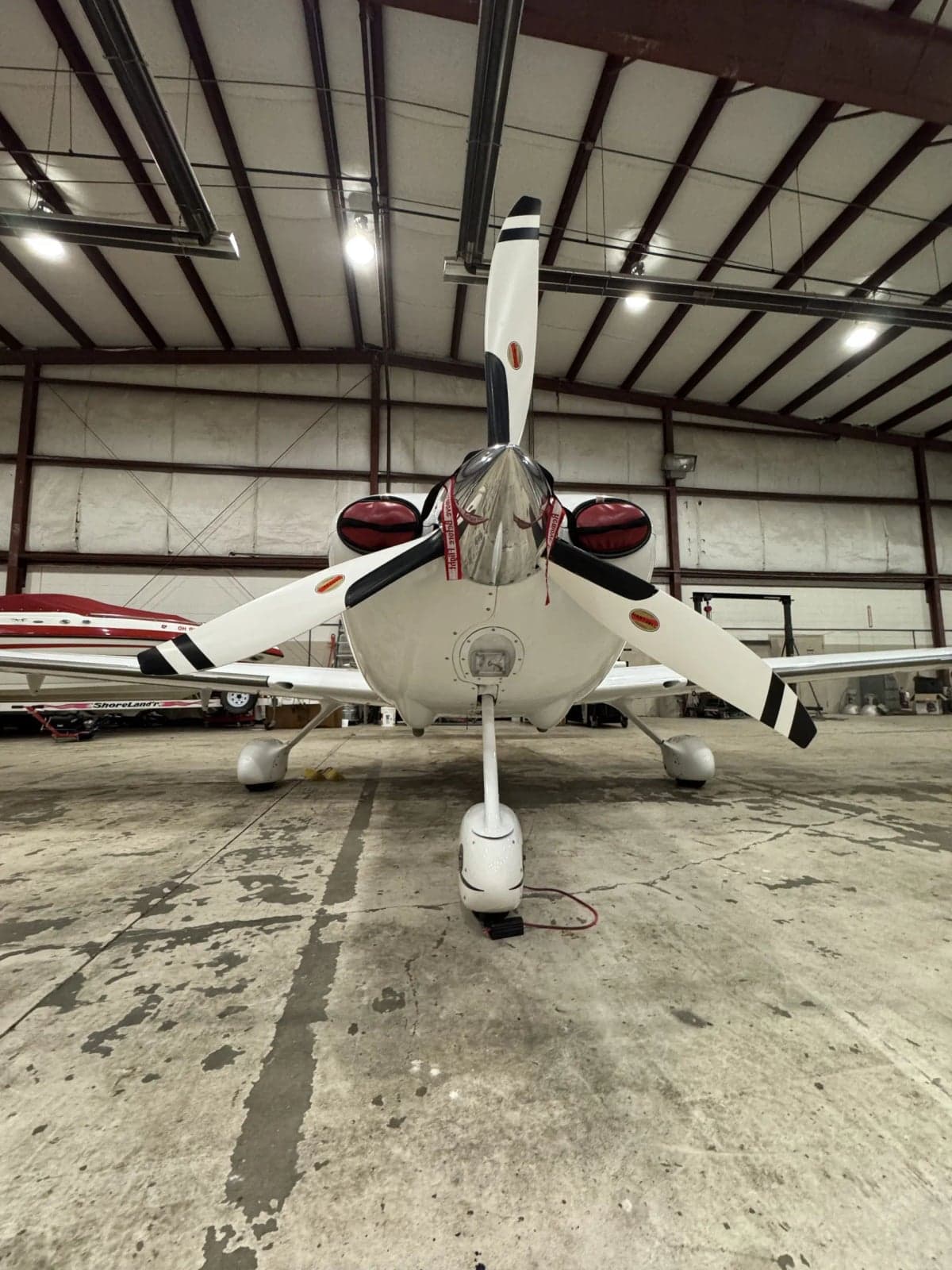 Front view of a Cirrus SR22T in a hangar, showing the propeller and landing gear.