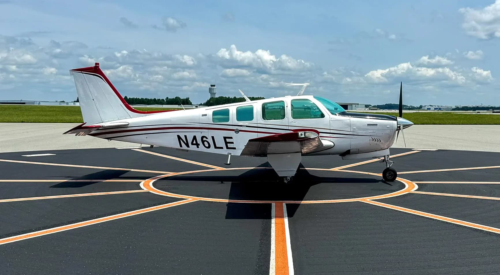 Beechcraft Bonanza with white and red paint scheme on a tarmac.