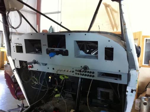 The bare instrument panel of an aircraft is being worked on.
