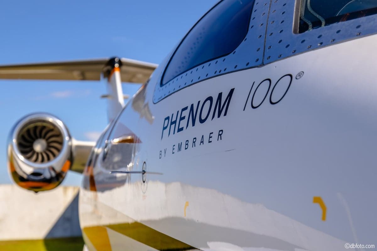 Close-up of the Phenom 100 logo on the side of the aircraft.