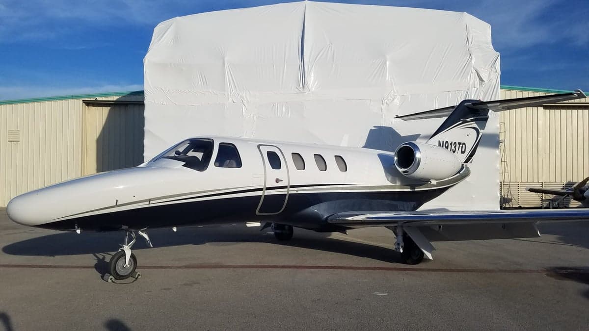 Exterior view of a Cessna CitationJet with a white and blue paint scheme.