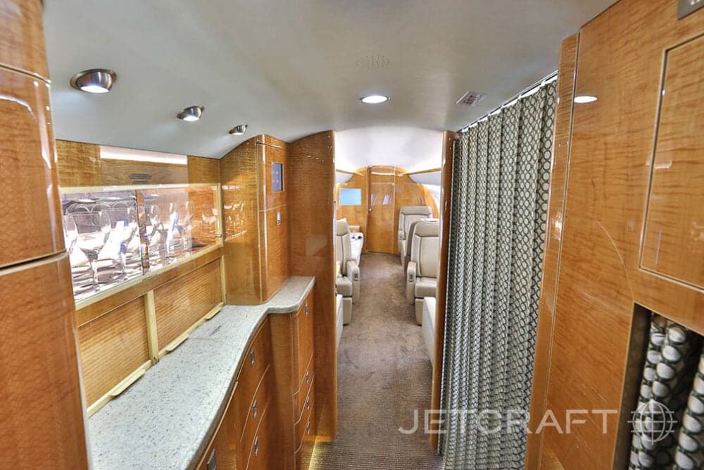 View down the aisle of the aircraft interior, showing the galley and seating area.