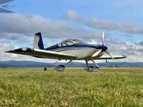 A blue and white aircraft is parked on the grass.