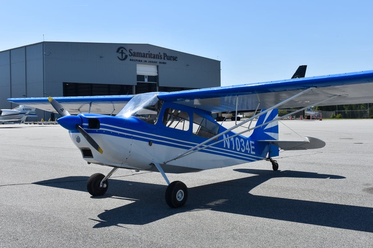 Front side view of a blue and white aircraft with tail number N1034E on the tarmac.