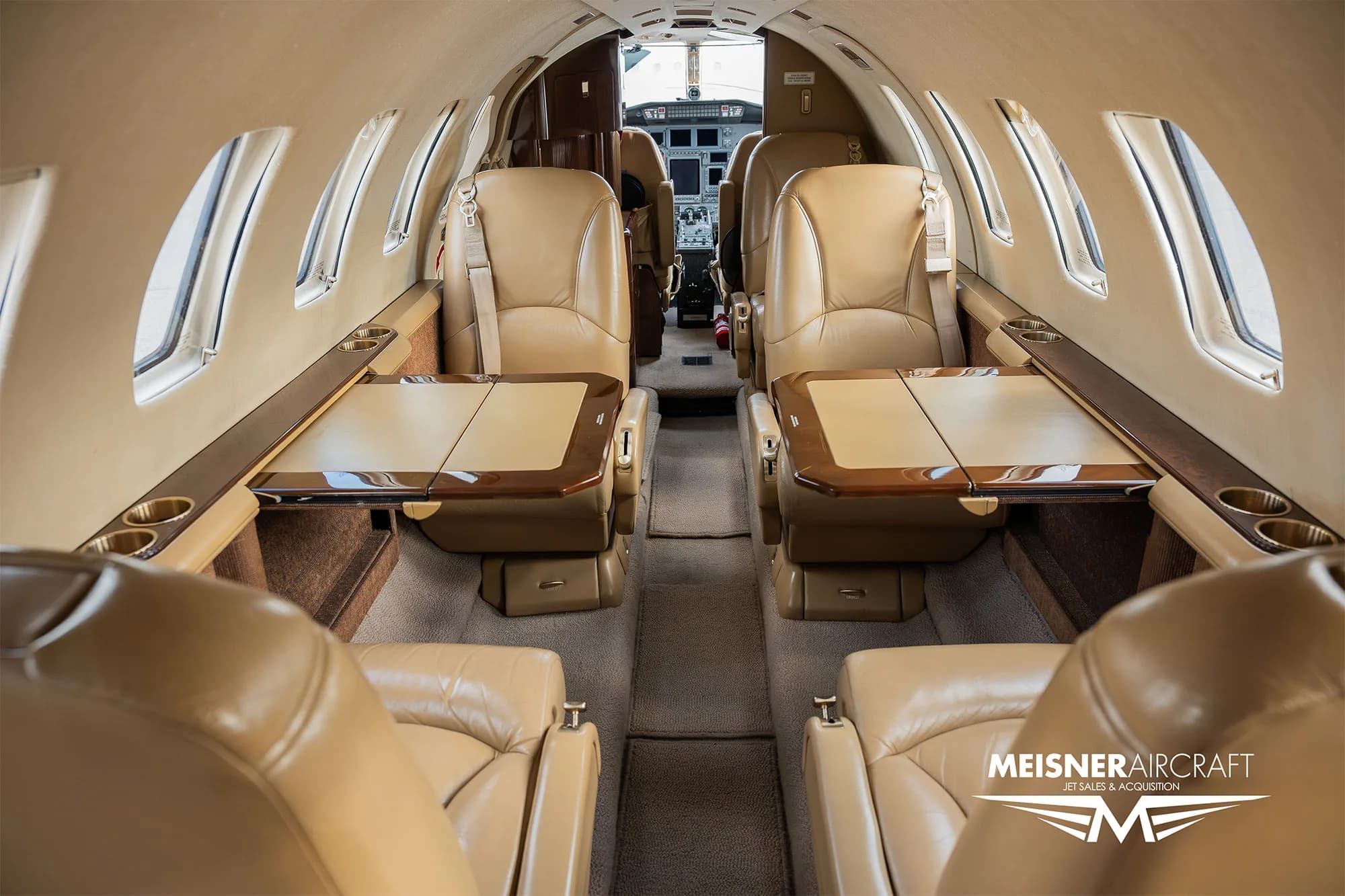 Interior view of a Cessna Citation Encore with tan leather seats and tables.