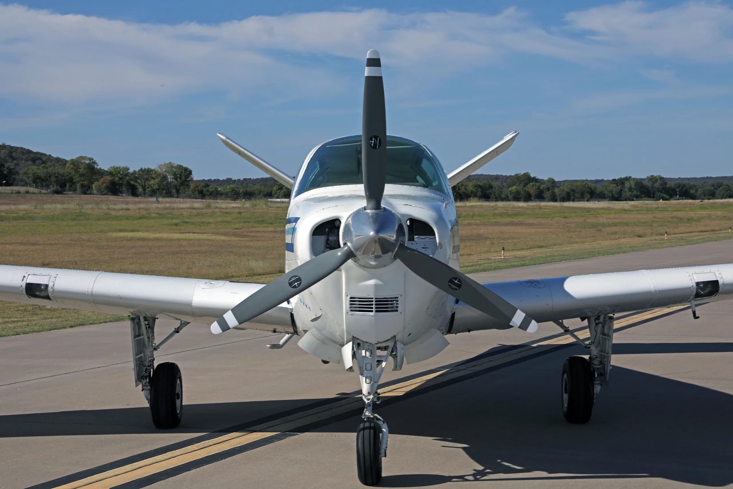 A head-on view of a white single-engine aircraft with a propeller, registration N4696D, parked on an airfield.