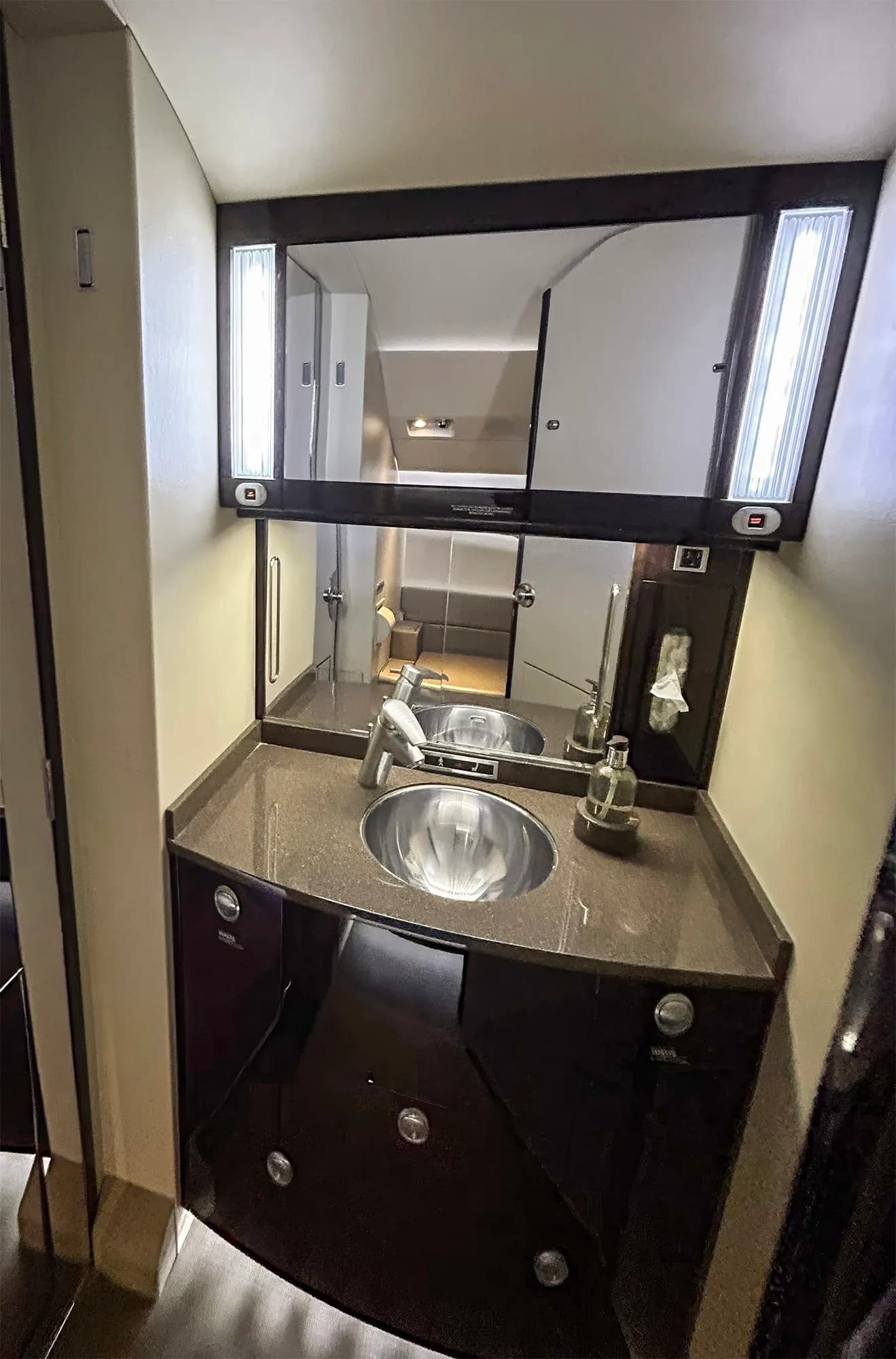 The lavatory vanity in a Dassault Falcon 900EX, with a modern sink, mirror, and dark wood cabinetry.