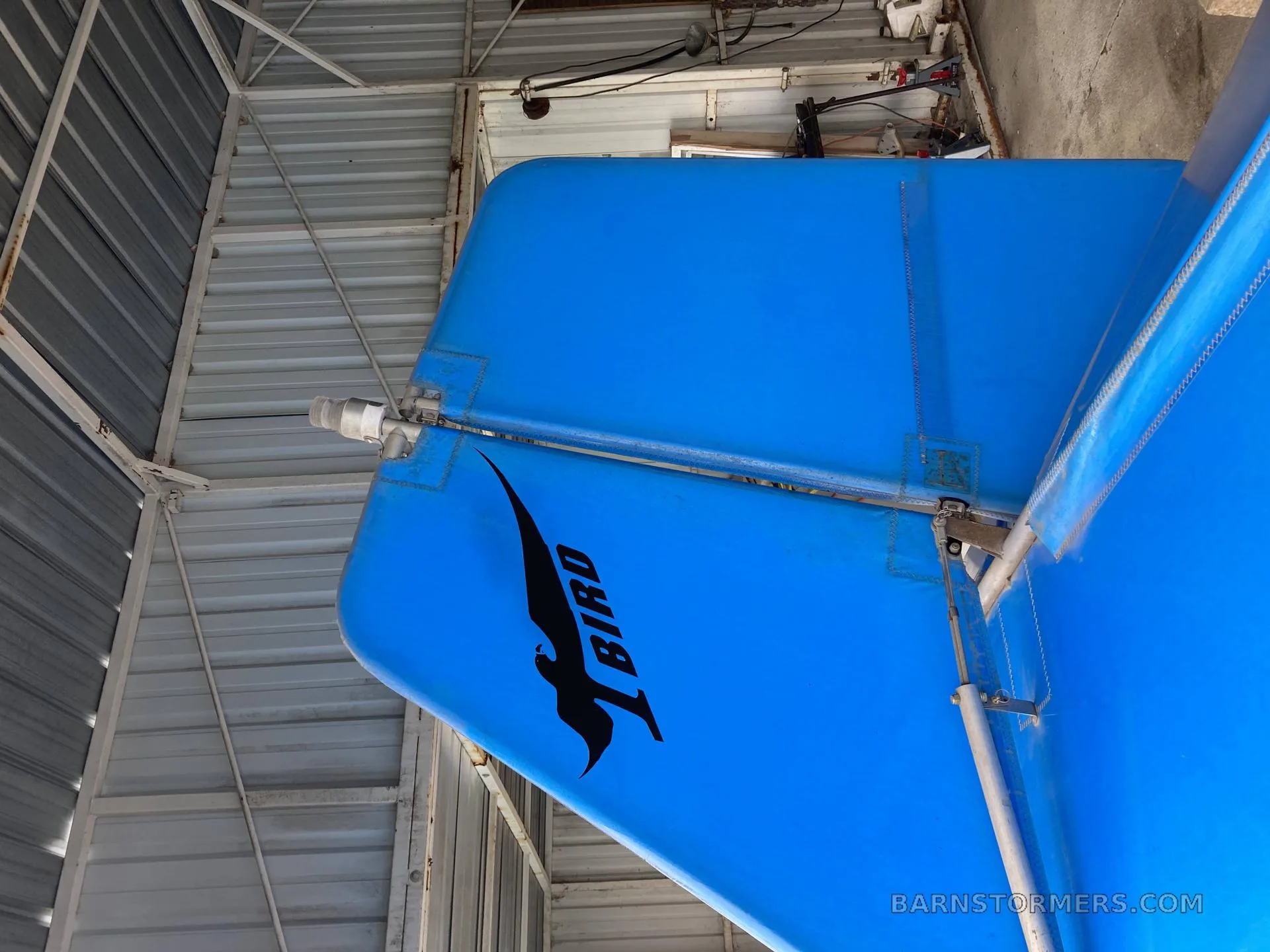 A close-up of the blue fabric tail of an ultralight aircraft, featuring a black "BIRD" logo.