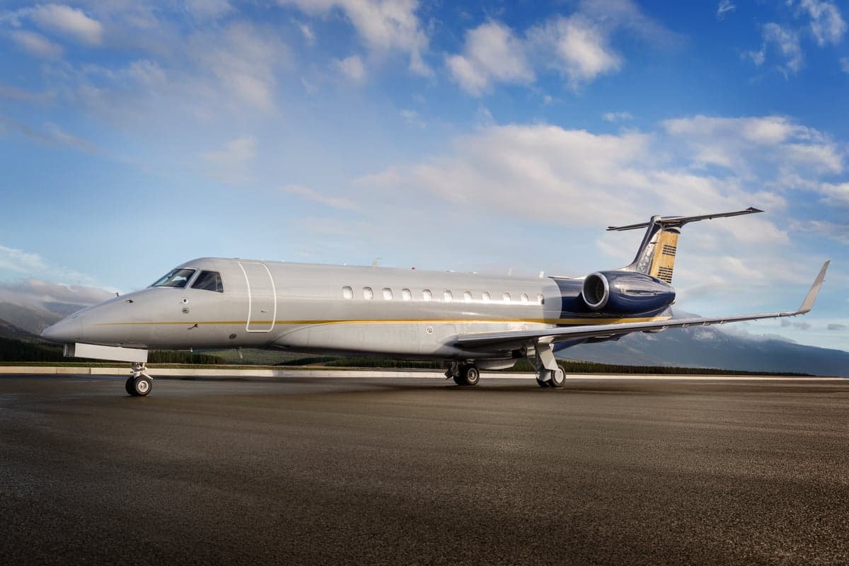 Embraer Legacy 500 on the tarmac with mountains in the background.