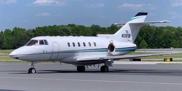 Side view of a white and blue Falcon jet on the tarmac.