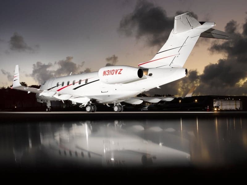 A Bombardier Challenger 350 aircraft with registration N310VZ is parked on the tarmac at dusk.