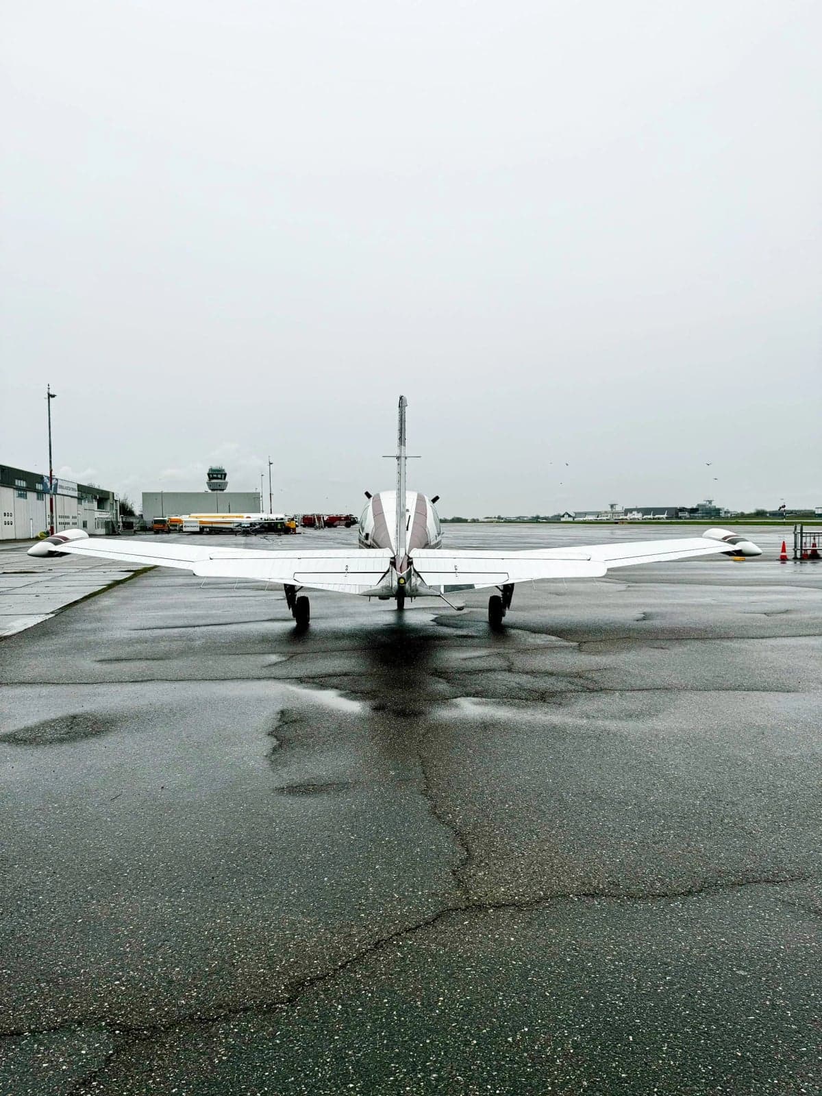 N100WS Bonanza aircraft parked on the tarmac with other aircraft in the background.