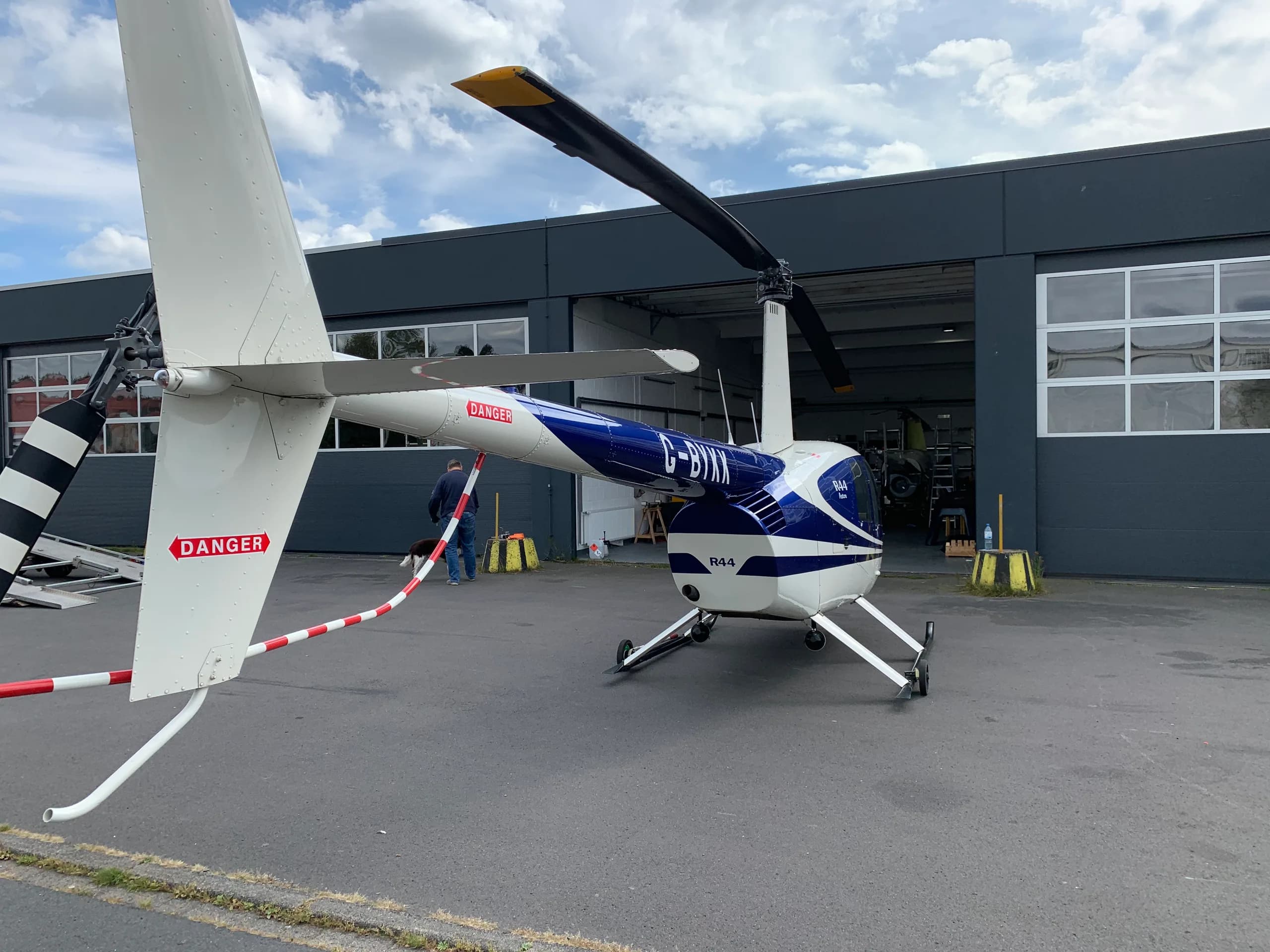 Rear view of a Robinson R44 Raven with blue and white paint scheme at an airport.
