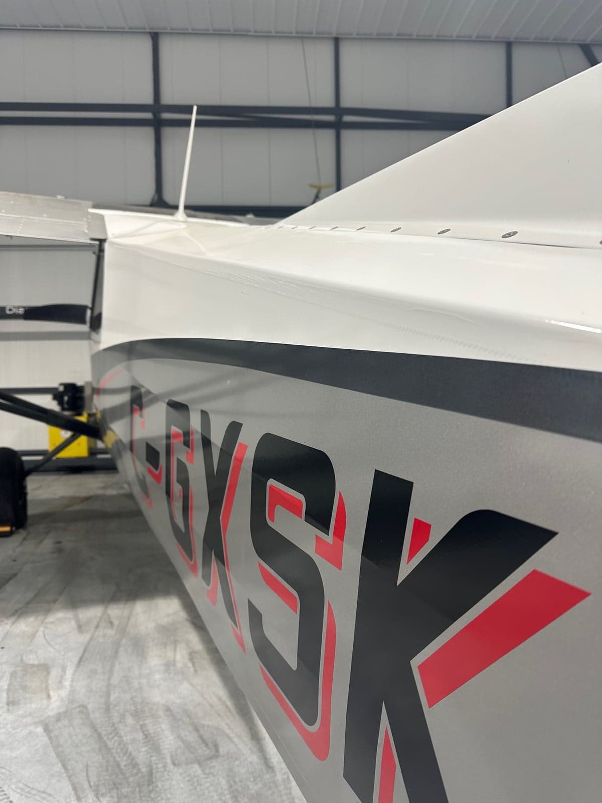 A close-up view of the fuselage of a white, grey, and red CubCrafters XCub aircraft, showing the registration C-GXSK.