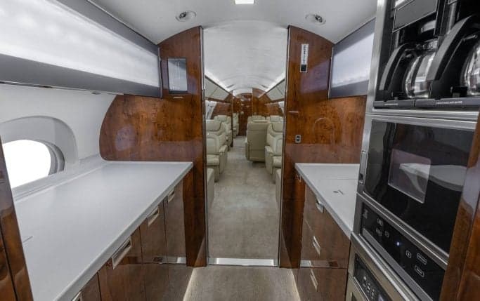 Aircraft cabin interior with leather seats and wood trim.