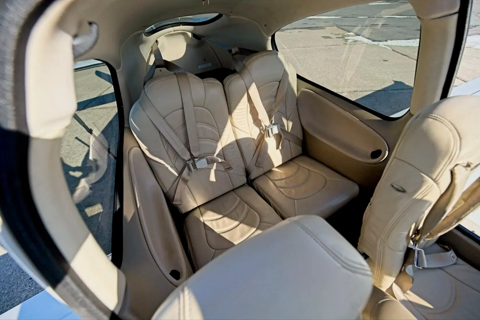 An angled view of the light tan leather rear seats of a Cirrus SR22 aircraft cabin.