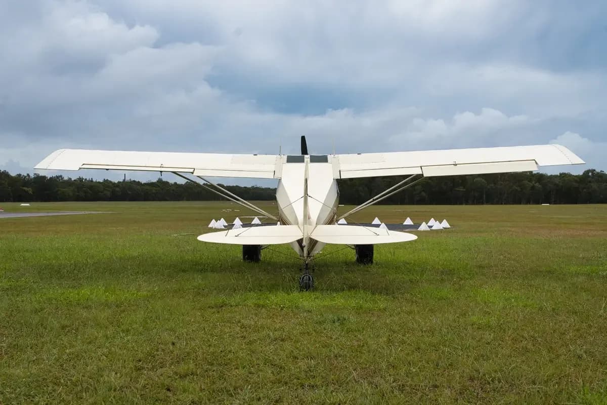 A cream and maroon single-engine taildragger aircraft with registration VH-TSY parked on a grassy airfield, viewed from the rear.