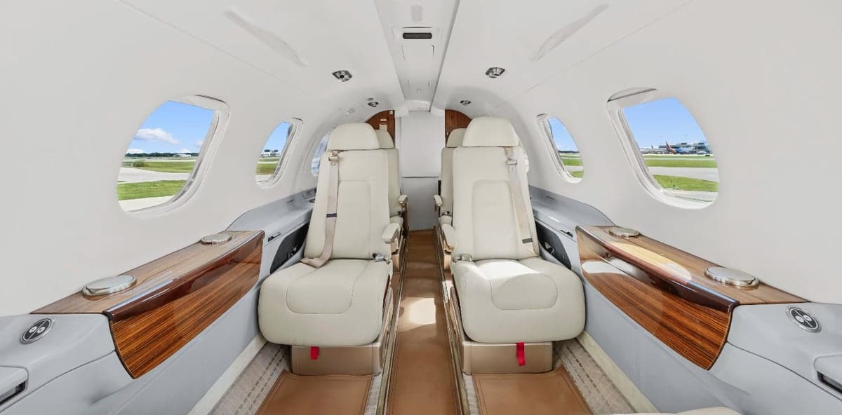 The interior of a Phenom 300 aircraft with seating and wood accents.