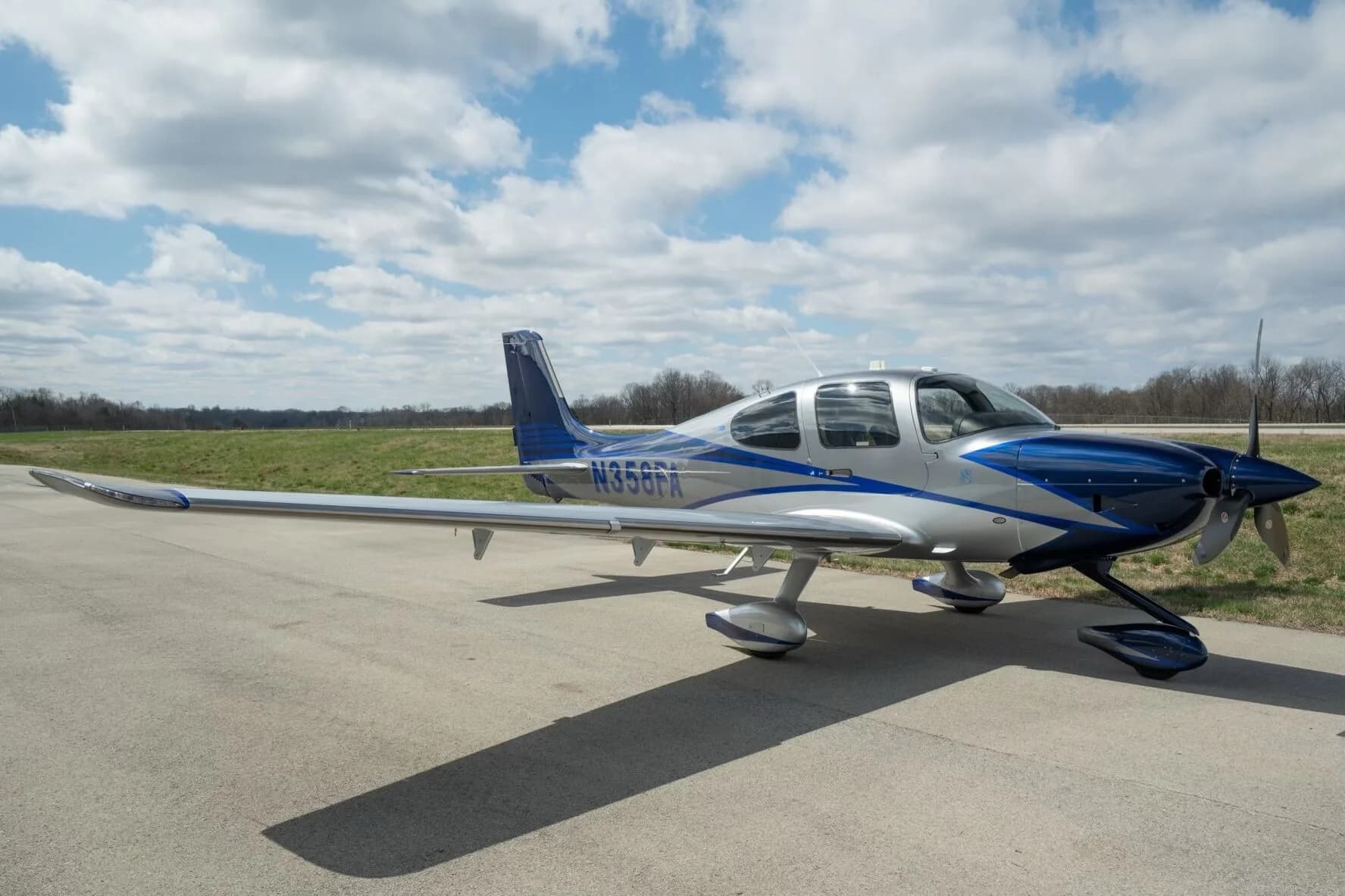 A silver and blue Cirrus SR22T aircraft, registration N358FA, parked on an airfield from a front-side angle.
